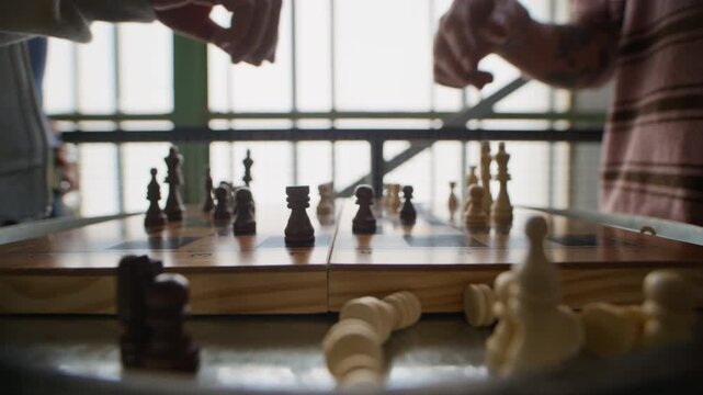 Close up of two players engaged in chess match on wooden board with removed pieces in foreground