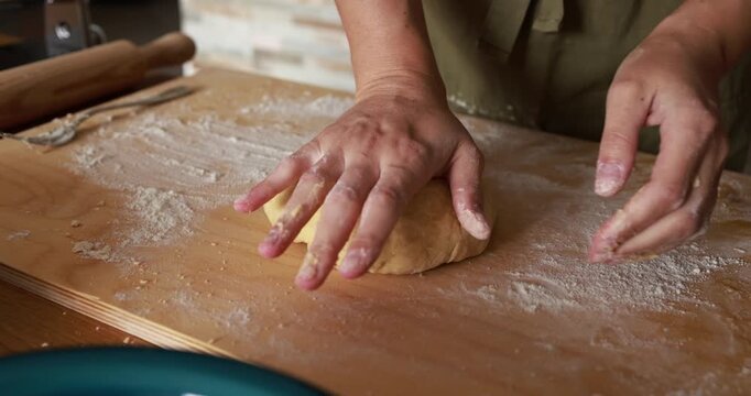 Woman kneading dough for handmade tagliatelle pasta indoor - Italian food, culture and lifestyle concept 