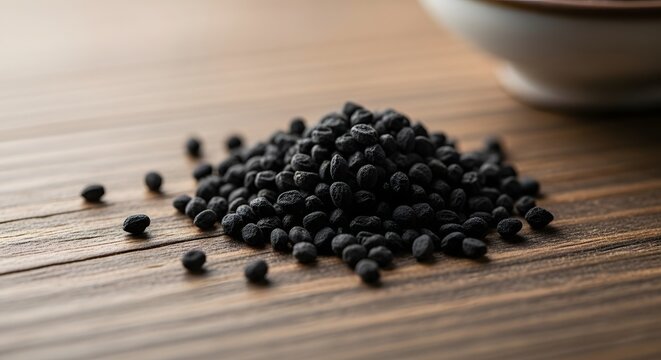 Close up shot of a pile of black cumin seeds on a wooden table
