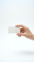 Fototapeta premium Hand holding blank white business card on clean background for corporate identity and branding mockup design projects.