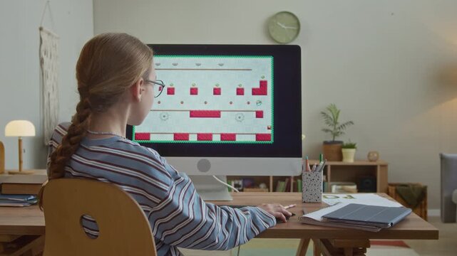 Back view of young Caucasian girl being interrupted by parental control lock while playing game on computer at home table