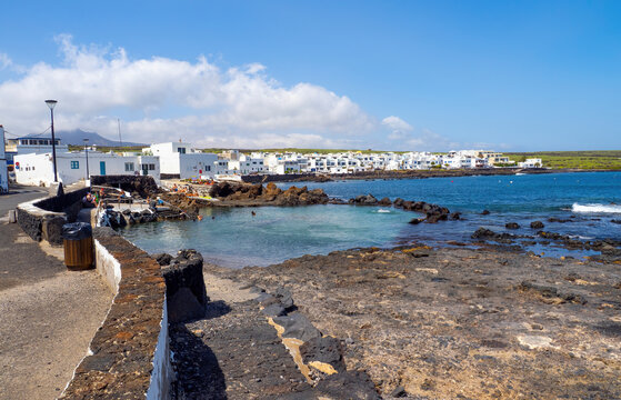 coastal bathing area in punta mujeres lanzarote with natural lava pools clear water swimmers and white village houses along the shoreline