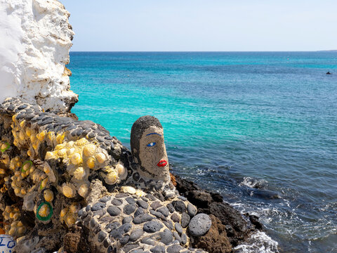 stone sculpture with shells on the coast of punta mujeres lanzarote overlooking turquoise atlantic water and volcanic rocks