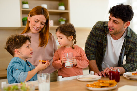 Family having breakfast together and talking in kitchen