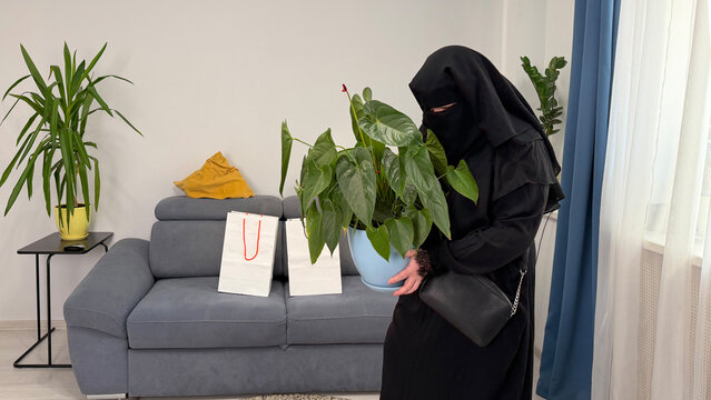 Muslim woman holding house plant at home lifestyle scene