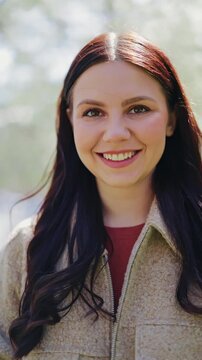 Woman radiates happiness, bright smile and joyful laugh. Captures cheerfulness in outdoor setting. Beautiful long hair and positive expression.