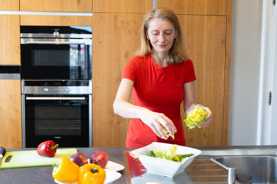 happy woman in her forties making a salad