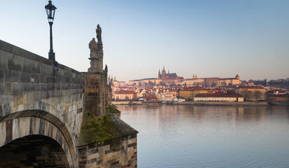 Obraz premium scenic view of Prague Castle and Charles Bridge glowing in golden light over the Vltava River