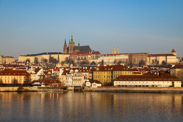 Obraz premium scenic view of Prague Castle and Charles Bridge glowing in golden light over the Vltava River