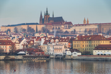 Obraz premium scenic view of Prague Castle and Charles Bridge glowing in golden light over the Vltava River
