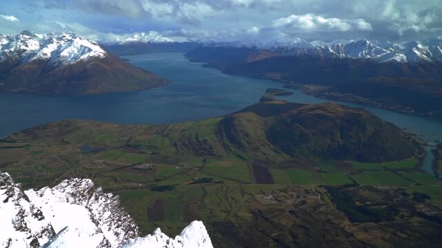 The Remarkables Ski Resort look out jagged snowy covered peaks Rock face cold winter morning sunny blue sky clouds New Zealand Lake Wakatipu Queenstown Frankton lush green valley blowing snow pan