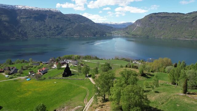 Urnes Stave Church above Lustrafjord in Luster Norway with green hills and fjord landscape