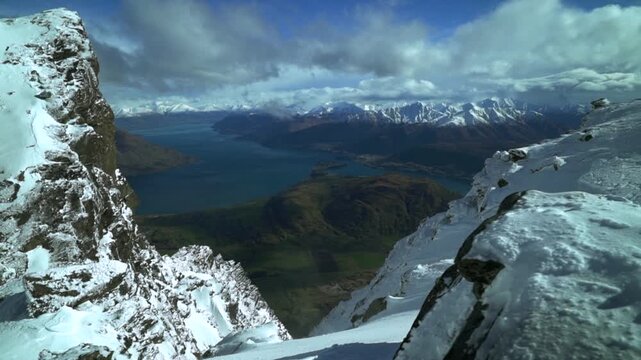 Look out The Remarkables Ski Resort jagged snowy covered peaks Rock face cold winter morning sunny blue sky clouds New Zealand Lake Wakatipu Queenstown Frankton lush green valley blowing snow slide