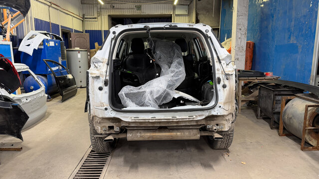 Stripped car body in auto repair workshop rear view