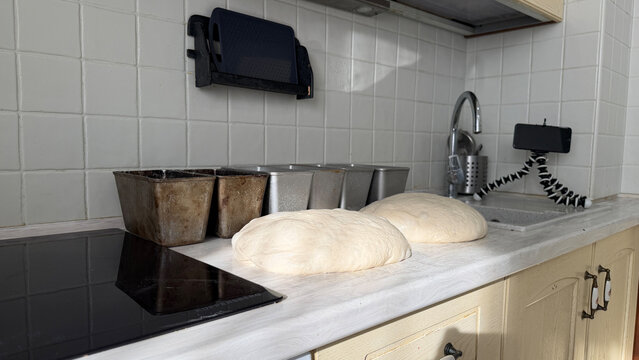 Sourdough dough portions on a kitchen countertop with smartphone. Concept of bread recipes and online baking education.