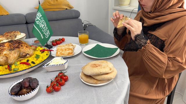 Muslim woman eating Mutabbaq with traditional dishes during Iftar