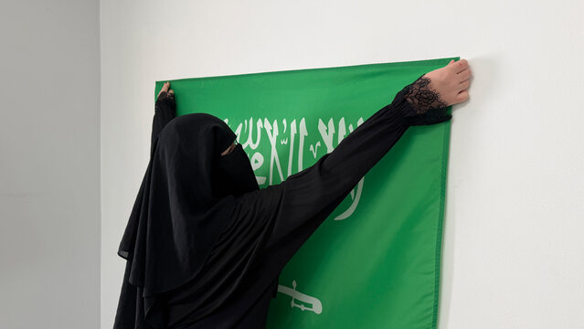 Saudi Arabia woman raising national flag indoors