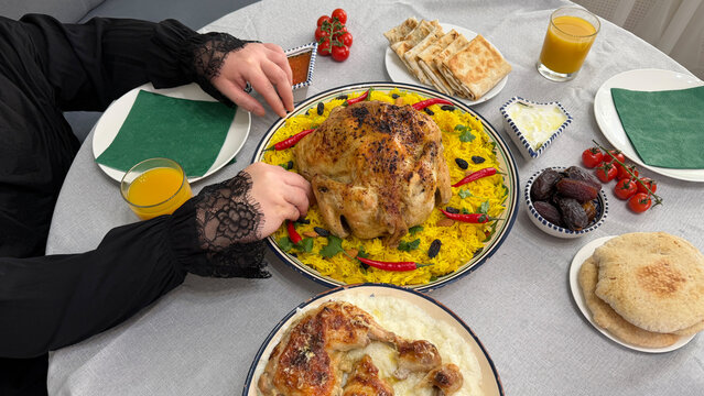Woman eating kabsa with her hands. Saudi Arabia: Kabsa rice with roasted chicken served on the Iftar table