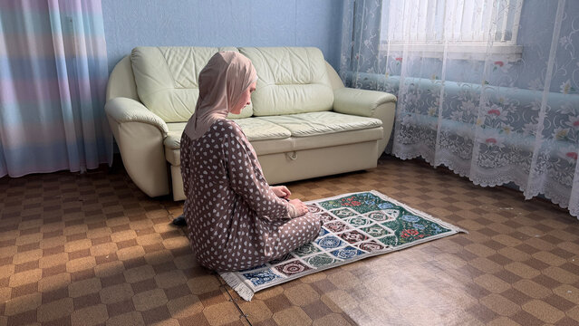 Saudi Arabia woman praying on prayer rug at home during Ramadan