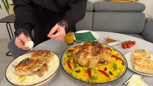 Close-up of person eating Kabsa rice with chicken and bread. Traditional Middle Eastern food experience.
