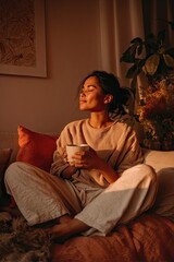 Obraz premium A woman with coffee sits relaxingly on the sofa at home