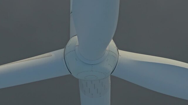 Close up of a large wind turbine rotating slowly, generating clean, renewable energy. The nacelle and blades are shrouded in thick fog
