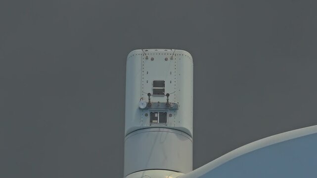 Close up of a large wind turbine generator rotating on a foggy day. The blades slowly turn, producing clean and renewable energy
