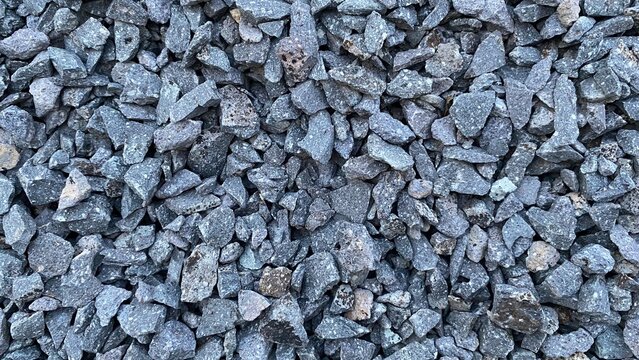 A pile of gravel with a rough texture and a natural gray color. Its shape is irregular and its details are sharp.