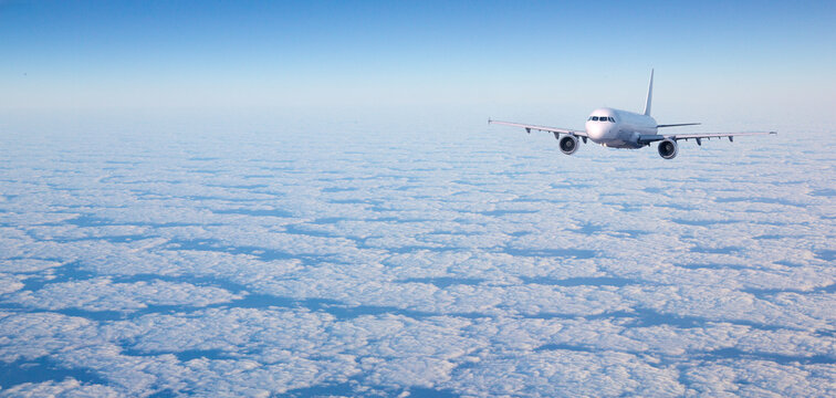 Airplane flying over clouds in clear sky