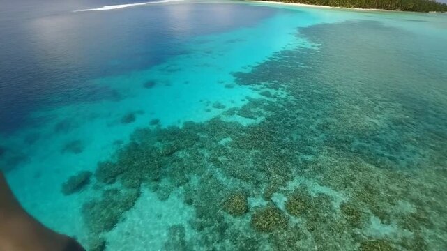 FPV drone gliding low over turquoise lagoon waters in Bora Bora, coral patterns visible
