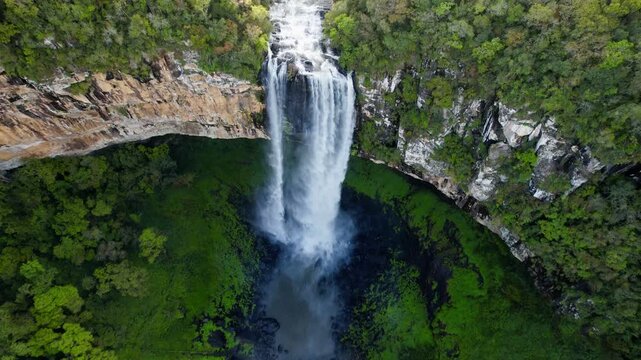 Drone view of tall waterfall cascade dropping into Atlantic forest gorge in Canela southern Brazil