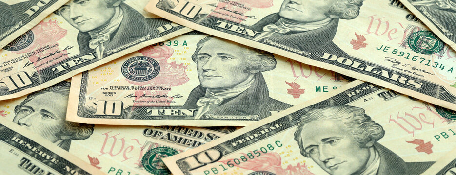 US ten dollar money banknotes pile on table. United States bills of USD currency close up