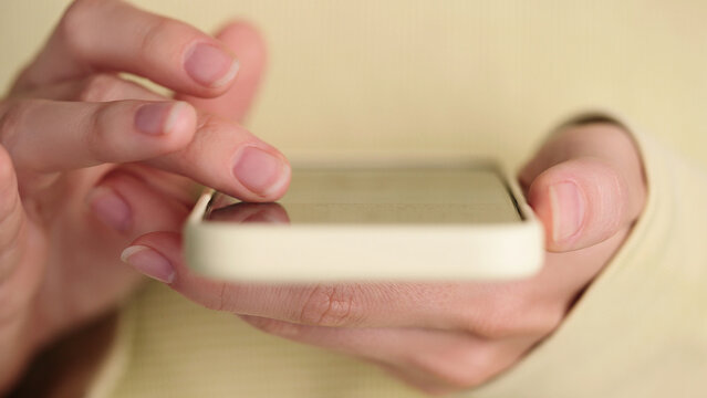 Close-up of girl using smartphone touchscreen. Prompts AI agent assistant. Finger tapping scrolling mobile app, browsing online video library, watching films internet. Modern digital lifestyle concept