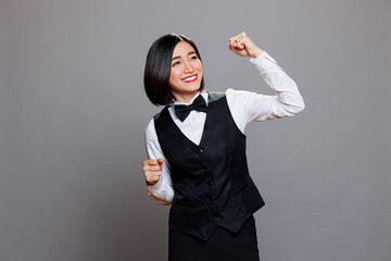 Cheerful asian waitress dressed in restaurant uniform dancing with joyful facial expression. Cafe smiling woman employee making moves with hands and body, spreading happiness