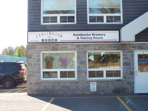 Nepean, Ontario, Canada &ndash; July 27, 2025: The "Carlington Booch" storefront features a horizontal sign for a kombucha brewery, gray stone walls, large windows, and white doors at 81 Auriga Dr #4.