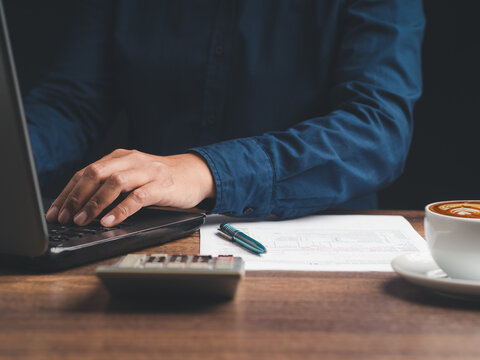 Business person typing on laptop with coffee at desk