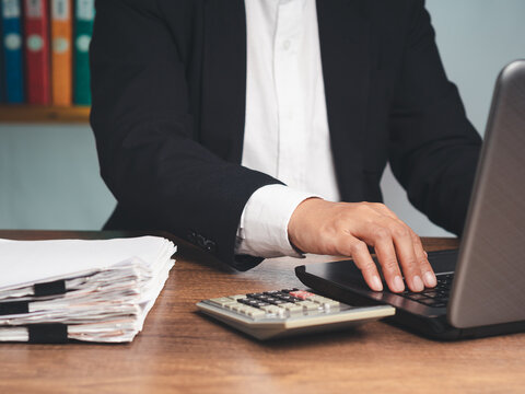 Business person working on laptop with financial documents