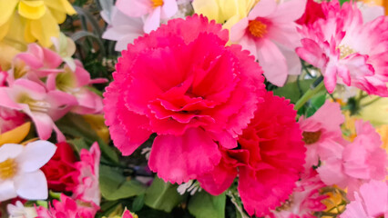 Obraz premium Close up view of vibrant artificial carnation flowers and mixed floral blossoms in a decorative bouquet arrangement