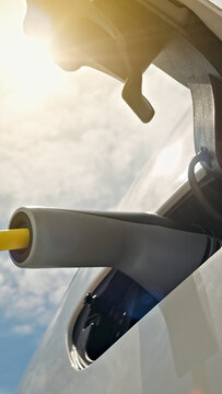 A sleek electric car is charged at a modern station, sunlight gleaming off its surface while a charging cable highlights renewable energy integration.