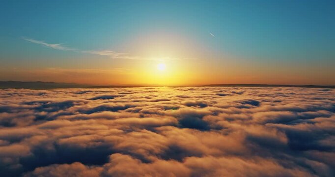 High angle view above clouds sunset sky summer. Fluffy white cloudscape sun shining bright orange. Dreamy heaven landscape travel tourism concept. Aerial drone flight freedom peace nature beauty scene
