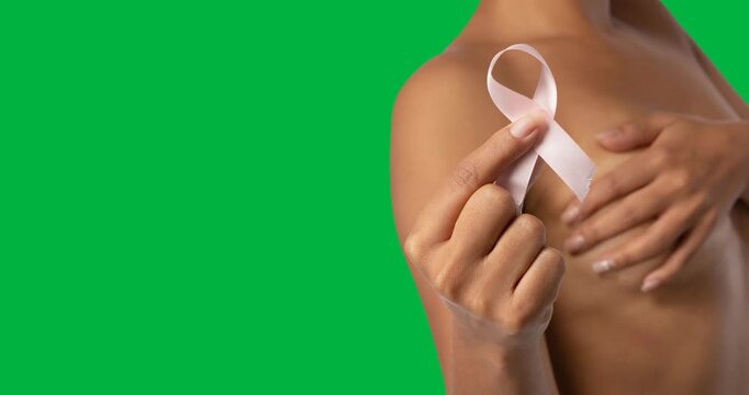 Mid section of naked woman covering her breasts and holding a ribbon against black background