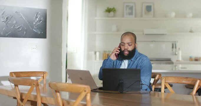 Vertical video: Taking work call, man in denim toggling between phone and laptop at dining table