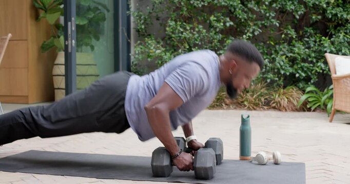 Man gripping dumbbells doing pushups on mat shifting into pike and kneeling, stretching for fitness