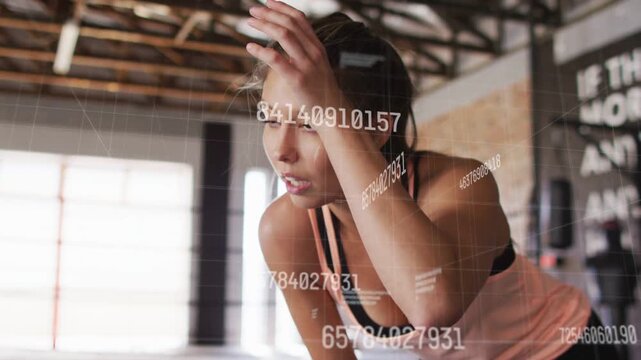 Vertical video: Woman catching breath after set in gym, numeric overlays tracking performance