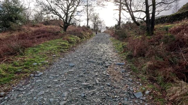 Point of view walking along a rocky pathway in the Lake District with wide mountain landscape views UK