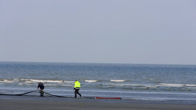 Shrimp fishermen pulling nets on beach in Nieuwpoort, Belgium - cinematic coastal fishing footage