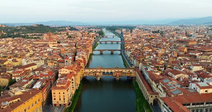 Panoramic perspective of the Arno river in Florence featuring historic bridges. Wide aerial view ancient city architecture residential districts in the morning light. Iconic European landmark travel