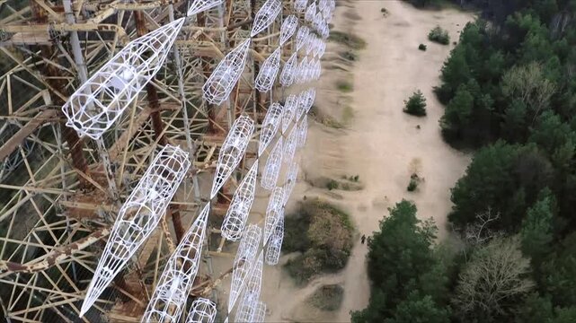 Two people walking along a path next to the abandoned Soviet Duga radar system near Pripyat