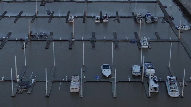 Aerial view of boats docked in a marina with calm water reflecting the gray sky, creating a serene yet muted scene, Dayton, Kentucky, United States.