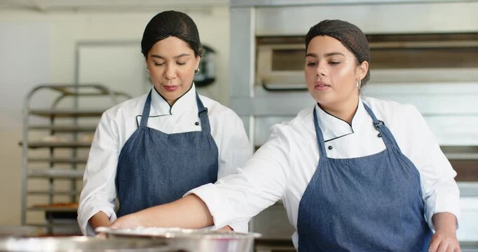 Female bakers in jackets right baker taking basket dusting flour kneading dough for oven at counter